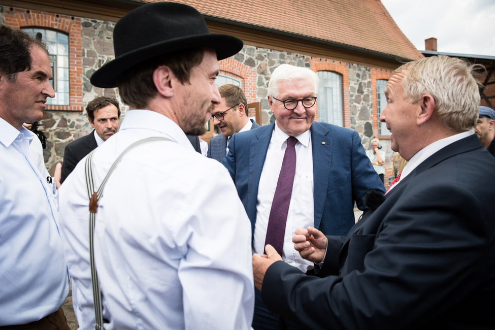 Bundespräsident Frank-Walter Steinmeier und Landwirtschaftsminister Till Backhaus sprechen mit Vertretern der Höfegemeinschaft Pommern.